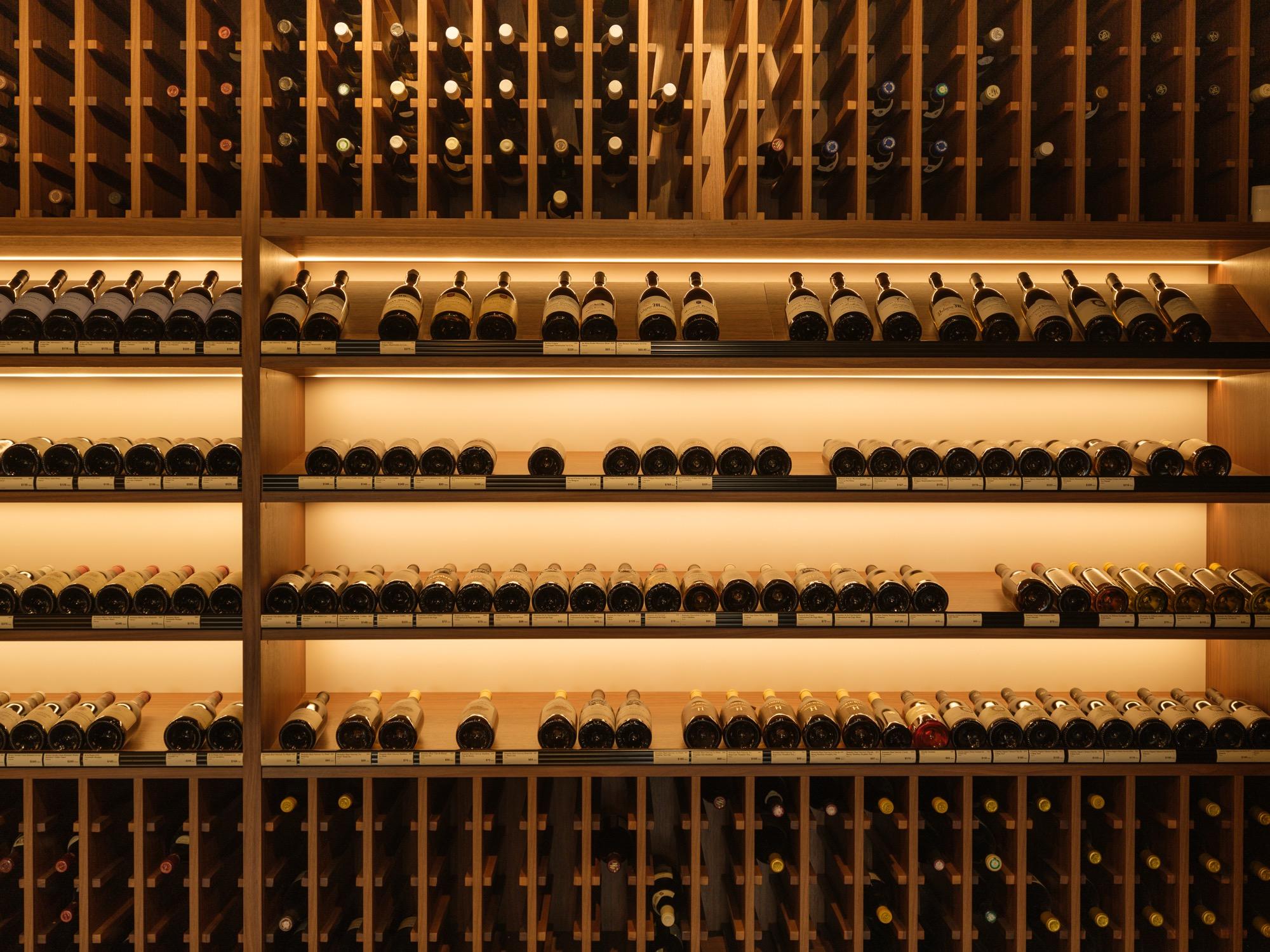 The lit cellar wall of collector bottles in our Calgary shop